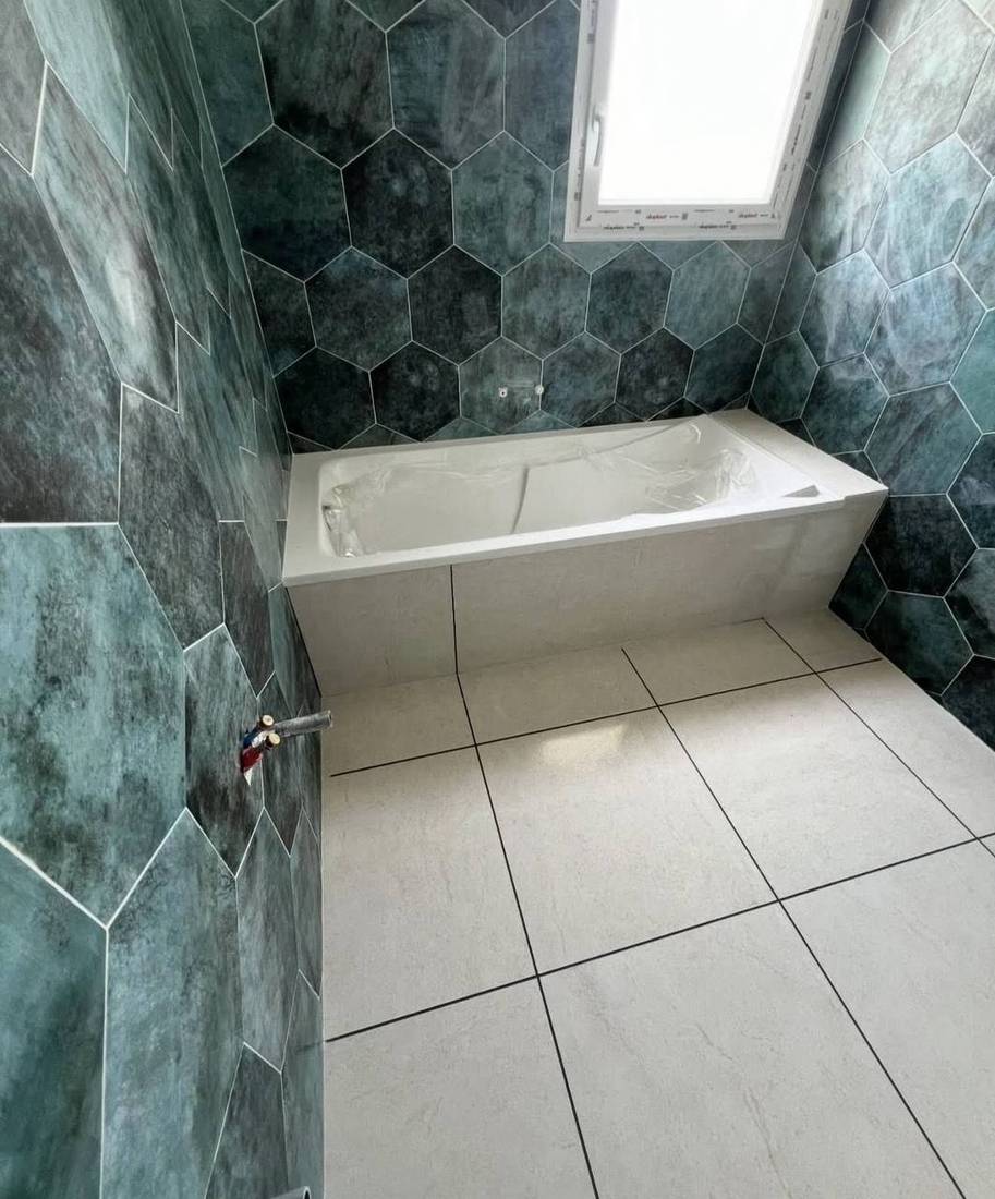 Salle de bains en faïence hexagonale verte avec tablier de baignoire carrelé